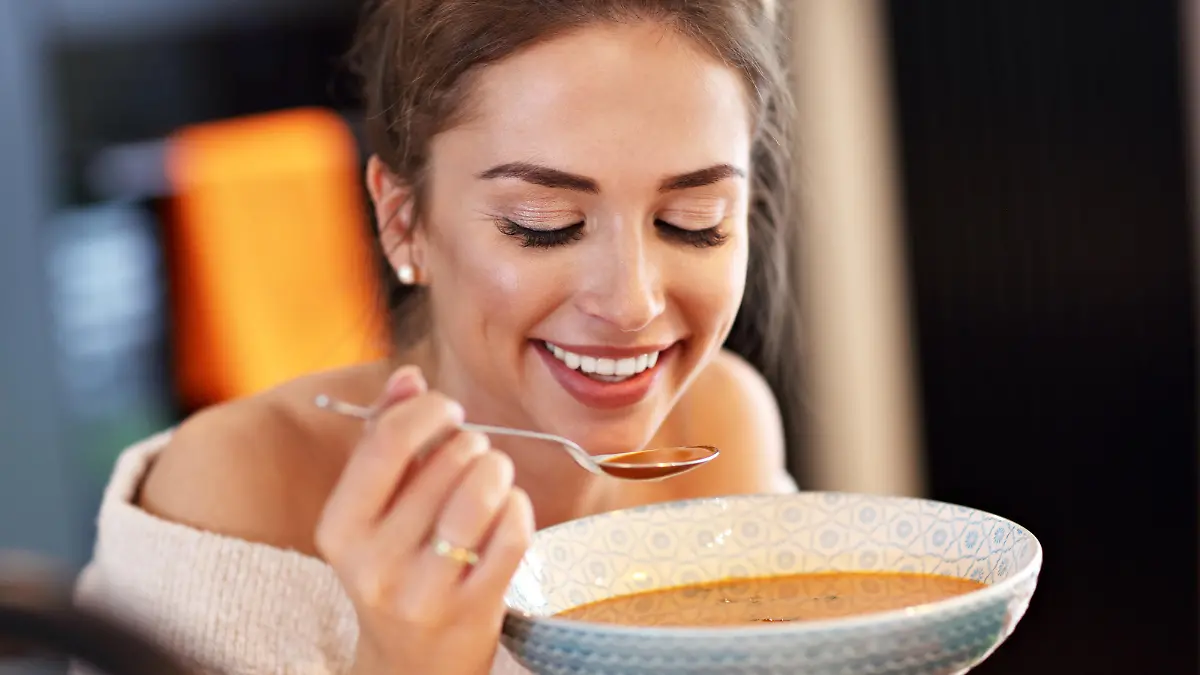 Picture of adult woman tasting pumpkin soup in the kitchen