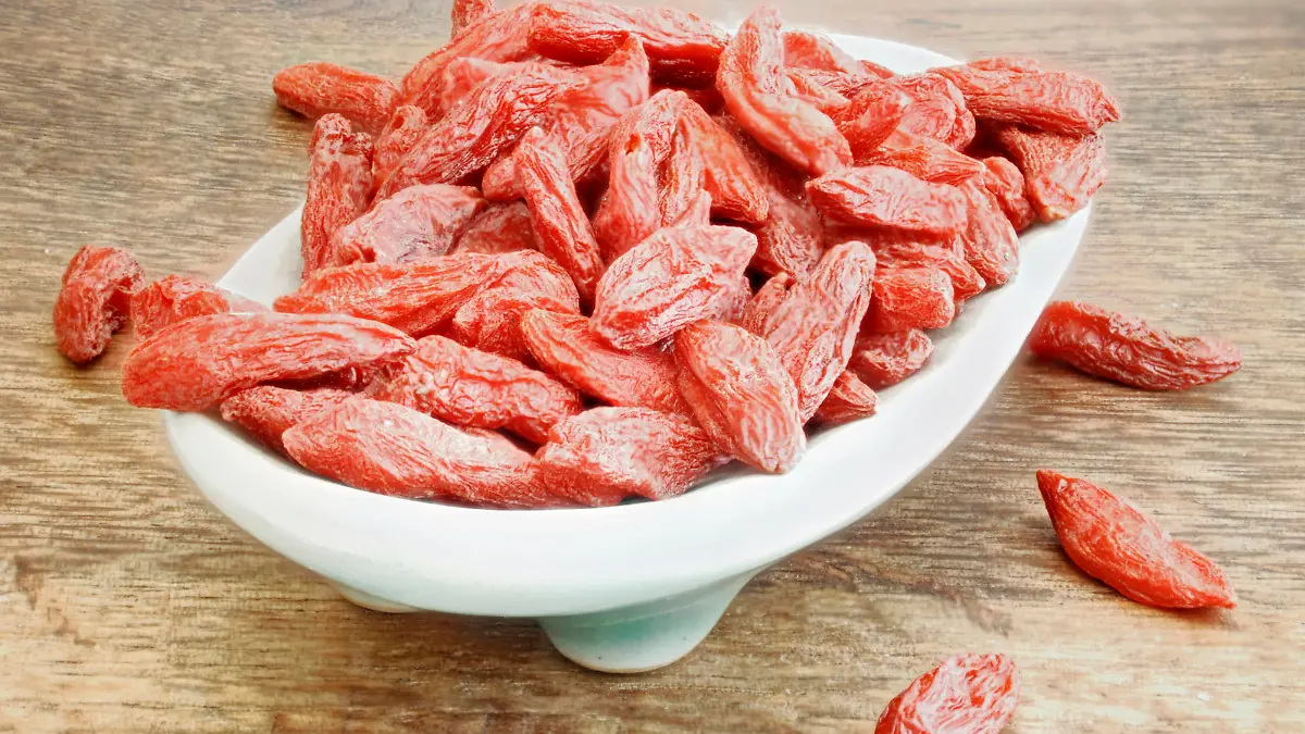 eine Schale mit Goji Beeren auf einem braunen Holztisch.