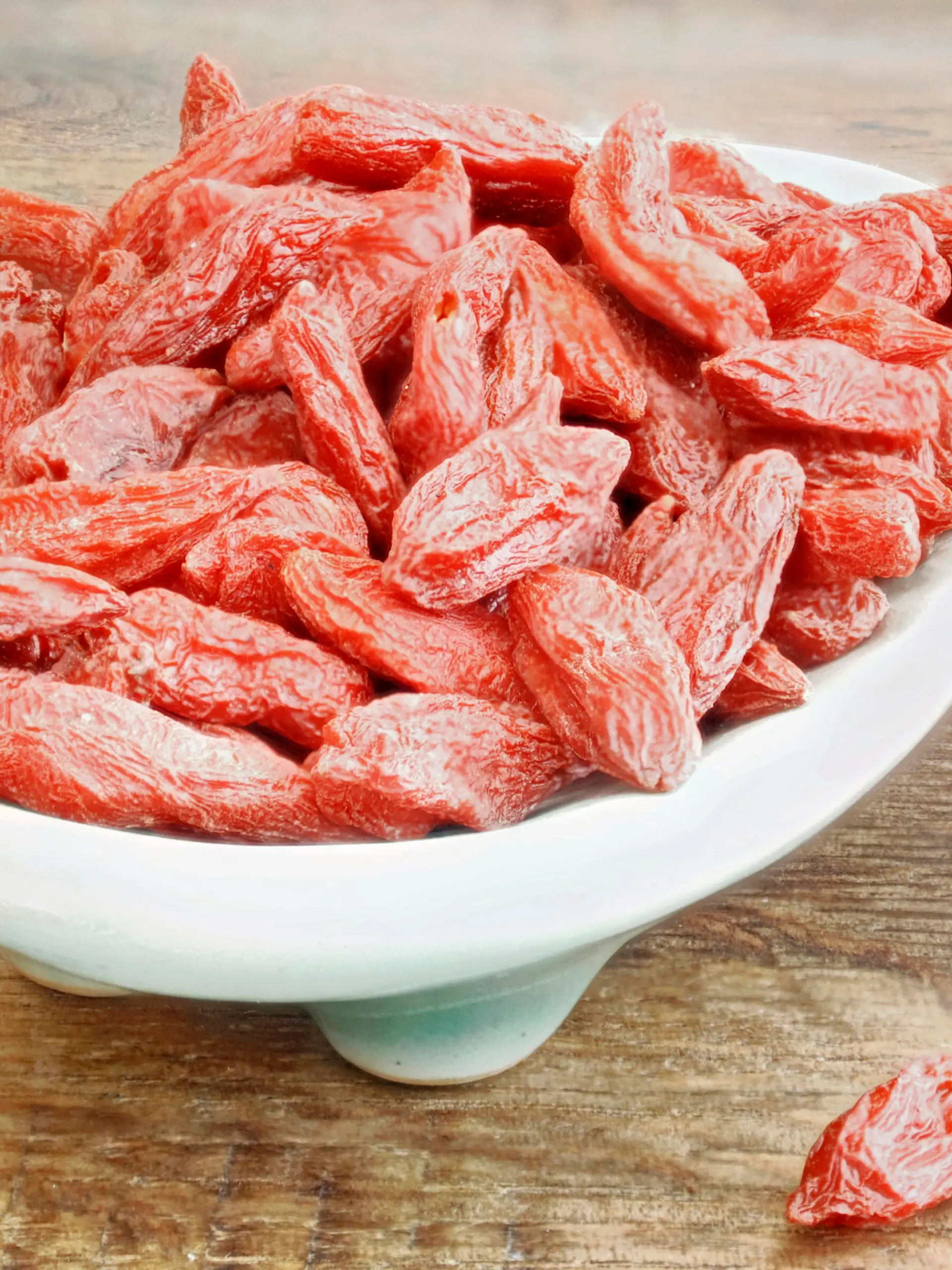 eine Schale mit Goji Beeren auf einem braunen Holztisch.