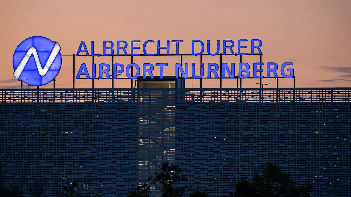Der Schriftzug «Albrecht Dürer Airport Nürnberg» leuchtet auf dem Dach eines Parkhauses am Flughafen.