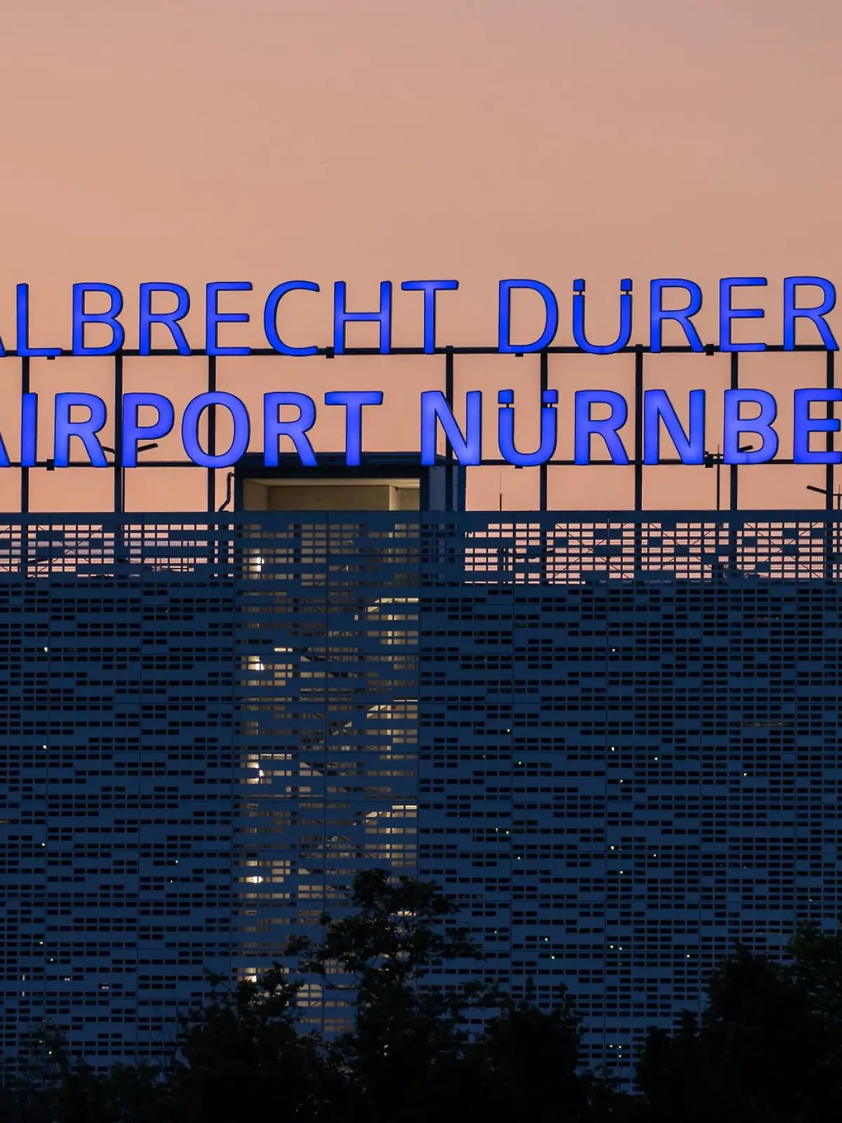 Der Schriftzug «Albrecht Dürer Airport Nürnberg» leuchtet auf dem Dach eines Parkhauses am Flughafen.