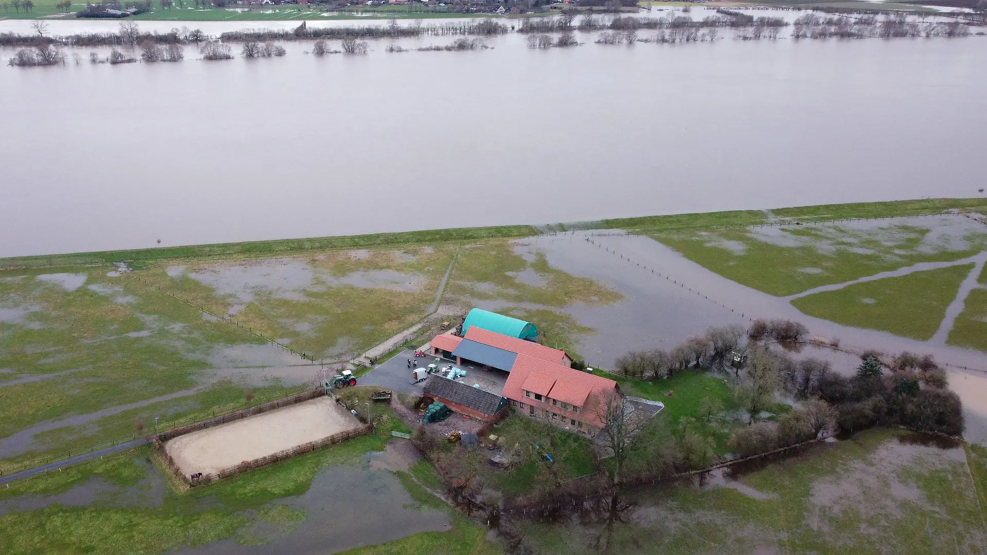 PRODUKTION - 04.01.2024, Niedersachsen, Hagen-Grinden: Der Hof von Familie Brake nahe dem Deich der Weser (Luftaufnahme mit einer Drohne). Die Ortschaft Hagen-Grinden bei Bremen war durch das Hochwasser tagelang von der Außenwelt abgeschnitten. Foto: Christof Dathe/dpa +++ dpa-Bildfunk +++