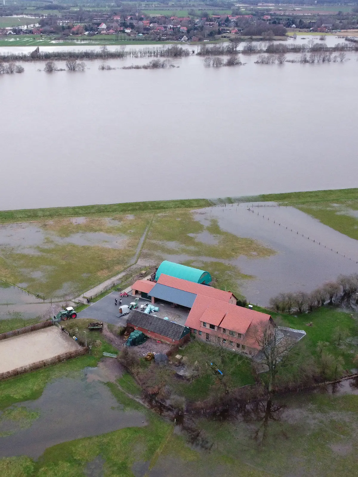 PRODUKTION - 04.01.2024, Niedersachsen, Hagen-Grinden: Der Hof von Familie Brake nahe dem Deich der Weser (Luftaufnahme mit einer Drohne). Die Ortschaft Hagen-Grinden bei Bremen war durch das Hochwasser tagelang von der Außenwelt abgeschnitten. Foto: Christof Dathe/dpa +++ dpa-Bildfunk +++