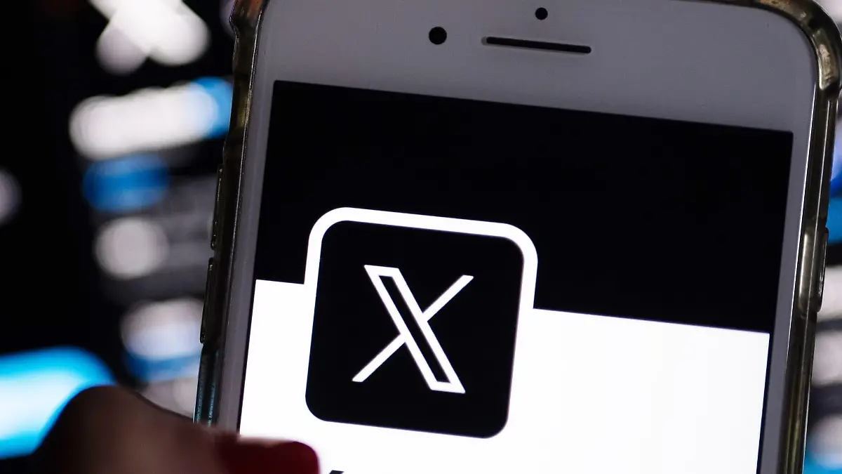Eine Frau öffnet die App von X (ehemals Twitter) auf ihrem Handy.