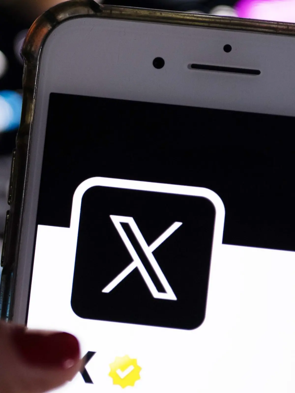 Eine Frau öffnet die App von X (ehemals Twitter) auf ihrem Handy.