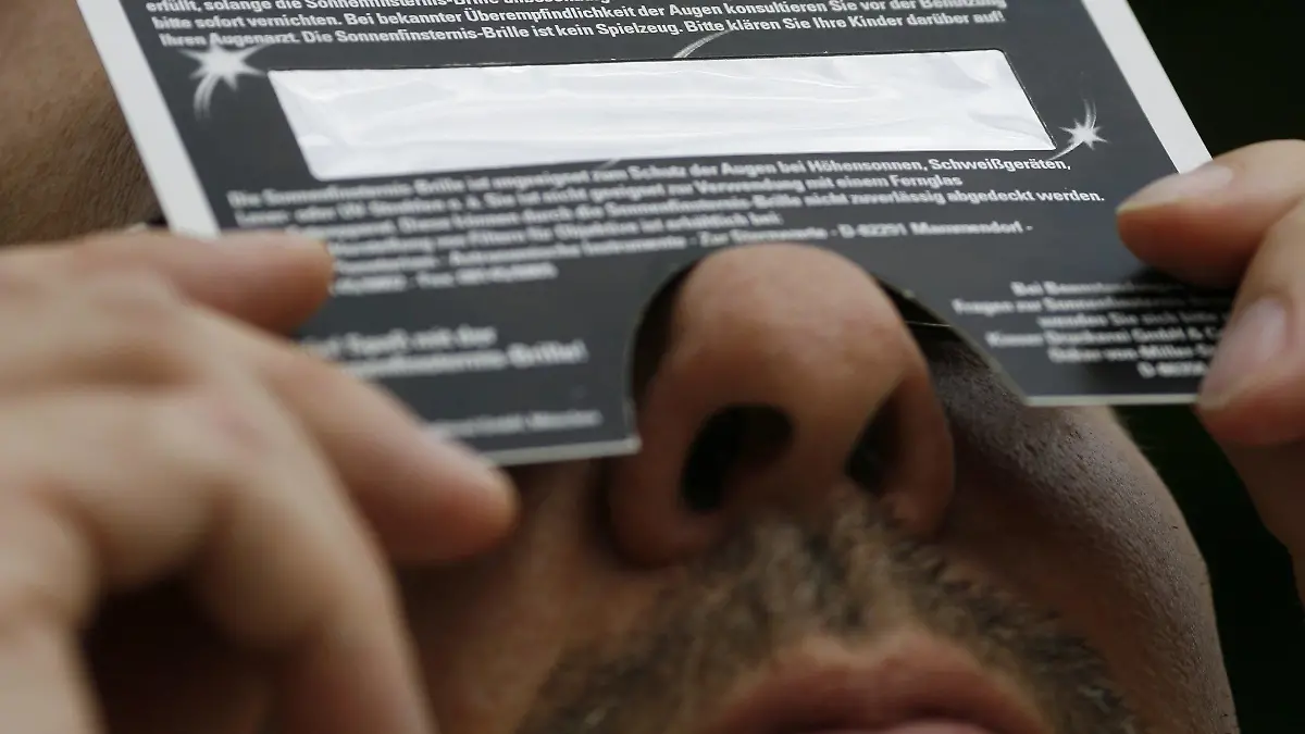 Mit einer speziellen Brille betrachtet am Freitag (01.08.2008) ein Mann in Magdeburg die partielle Sonnenfinsternis. Von etwa 10.30 Uhr und 12.45 Uhr findet in Mitteleuropa eine partielle Sonnenfinsternis statt. Derartige kosmische Schattenspiele entstehen immer dann, wenn sich der Mond zwischen Sonne und Erde schiebt und sein Schatten auf die Erde fällt. In Sachsen-Anhalt bedeckte der Mond die Sonne zu etwa 16 bis 17 Prozent, zu sehen war eine Art Einkerbung am linken oberen Rand der Sonne. Foto: Jens Wolf dpa/lah (zu lah 4190 vom 01.08.2008) +++(c) dpa - Bildfunk+++