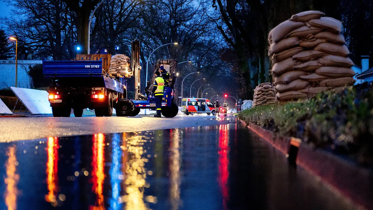dpatopbilder - 05.01.2024, Niedersachsen, Oldenburg: Einsatzkräfte des Technischen Hilfswerks (THW) laden bei Regen zahlreiche Sandsäcke an der Sandkruger Straße im Stadtteil Bümmerstede ab. Ein mobiler Deich soll die Wohngebiete im Stadtteil Bümmerstede vor einem drohenden Hochwasser schützen. Foto: Hauke-Christian Dittrich/dpa +++ dpa-Bildfunk +++