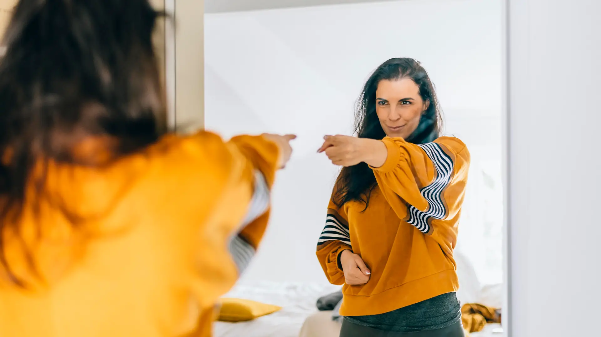 Self confident single woman pointing finger at her reflection in mirror, dancing and felling good. Independent person with high self esteem talks positive and I can do it motivation. Satisfied mother in 40s loved inspired and proud.