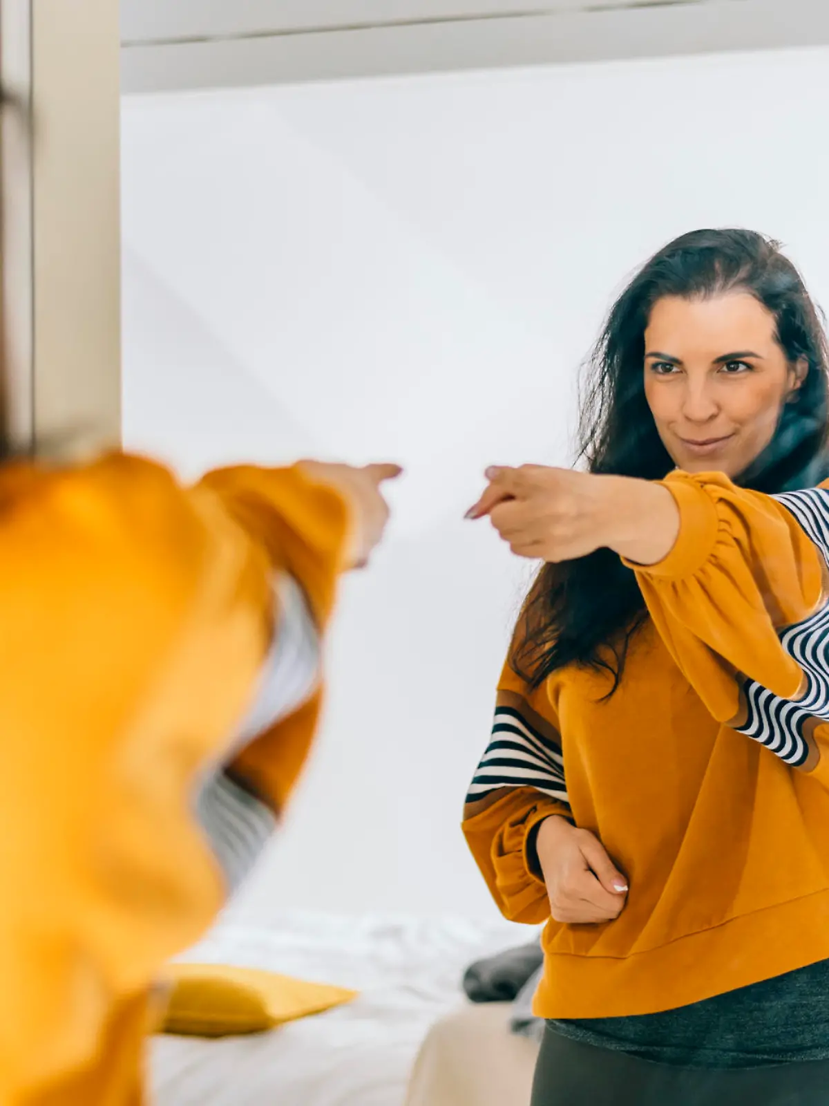 Self confident single woman pointing finger at her reflection in mirror, dancing and felling good. Independent person with high self esteem talks positive and I can do it motivation. Satisfied mother in 40s loved inspired and proud.