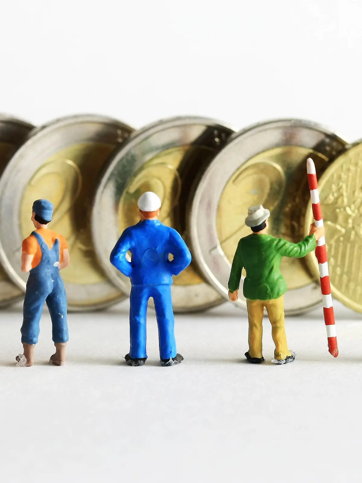  Symbolfoto Mindestlohn:Miniatur Figuren in Arbeitskleidung unterschiedlicher Branchen stehen vor Euro Geldmünzen im Wert von 8,50