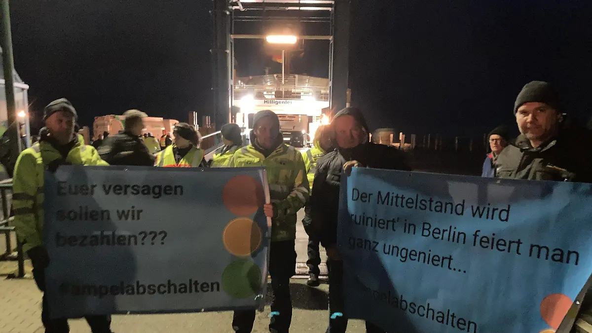 SCREENSHOT - 04.01.2024, Schleswig-Holstein, Schüttsiel: Landwirte stehen mit Plakaten mit der Aufschrift "Euer Versagen sollen wir bezahlen??? #ampelabschalten" am Fähranleger. Wütende Bauern hinderten Vizekanzler Robert Habeck (Grüne) in Schlüttsiel in Schleswig-Holstein am Verlassen einer Fähre. Wie ein Polizeisprecher der Deutschen Presse-Agentur sagtes, habe Habeck, der auch Wirtschaftsminister ist, deshalb wieder auf die Hallig Hooge zurückkehren müssen. Nach Angaben der Polizei handelte es sich um mehr als hundert Demonstranten. Foto: Hagen Wohlfahrt/Schleswig-Holsteinischer Zeitungsverlag/dpa - ACHTUNG: Nur mit vollständiger Nennung des vorstehenden Credits +++ dpa-Bildfunk +++