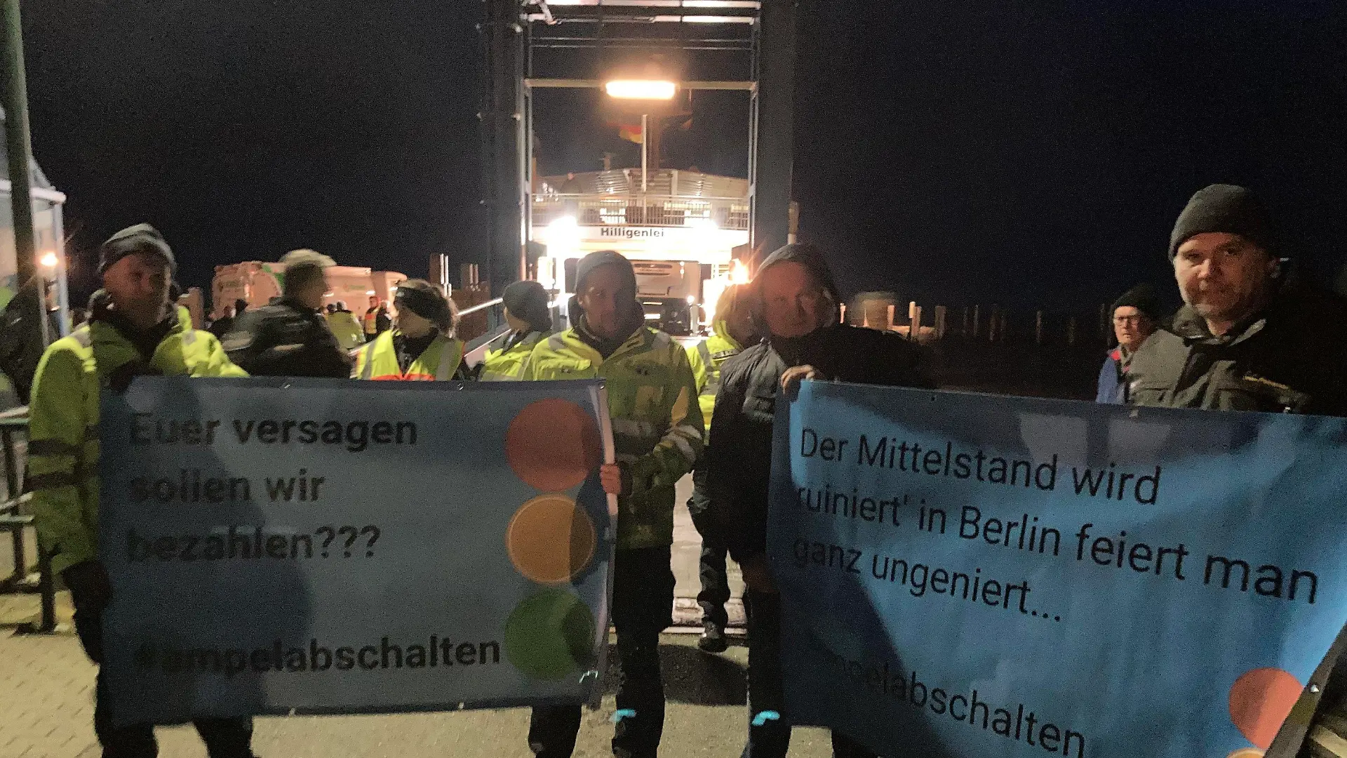 SCREENSHOT - 04.01.2024, Schleswig-Holstein, Schüttsiel: Landwirte stehen mit Plakaten mit der Aufschrift "Euer Versagen sollen wir bezahlen??? #ampelabschalten" am Fähranleger. Wütende Bauern hinderten Vizekanzler Robert Habeck (Grüne) in Schlüttsiel in Schleswig-Holstein am Verlassen einer Fähre. Wie ein Polizeisprecher der Deutschen Presse-Agentur sagtes, habe  Habeck, der auch Wirtschaftsminister ist, deshalb wieder auf die Hallig Hooge zurückkehren müssen. Nach Angaben der Polizei handelte es sich um mehr als hundert Demonstranten. Foto: Hagen Wohlfahrt/Schleswig-Holsteinischer Zeitungsverlag/dpa - ACHTUNG: Nur mit vollständiger Nennung des vorstehenden Credits +++ dpa-Bildfunk +++