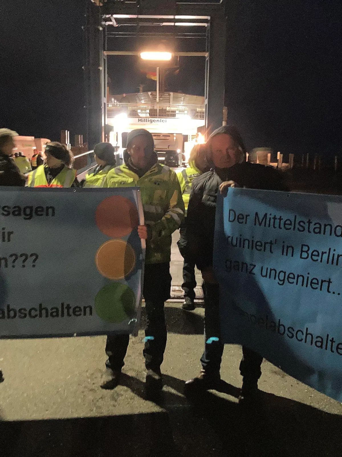 SCREENSHOT - 04.01.2024, Schleswig-Holstein, Schüttsiel: Landwirte stehen mit Plakaten mit der Aufschrift "Euer Versagen sollen wir bezahlen??? #ampelabschalten" am Fähranleger. Wütende Bauern hinderten Vizekanzler Robert Habeck (Grüne) in Schlüttsiel in Schleswig-Holstein am Verlassen einer Fähre. Wie ein Polizeisprecher der Deutschen Presse-Agentur sagtes, habe  Habeck, der auch Wirtschaftsminister ist, deshalb wieder auf die Hallig Hooge zurückkehren müssen. Nach Angaben der Polizei handelte es sich um mehr als hundert Demonstranten. Foto: Hagen Wohlfahrt/Schleswig-Holsteinischer Zeitungsverlag/dpa - ACHTUNG: Nur mit vollständiger Nennung des vorstehenden Credits +++ dpa-Bildfunk +++