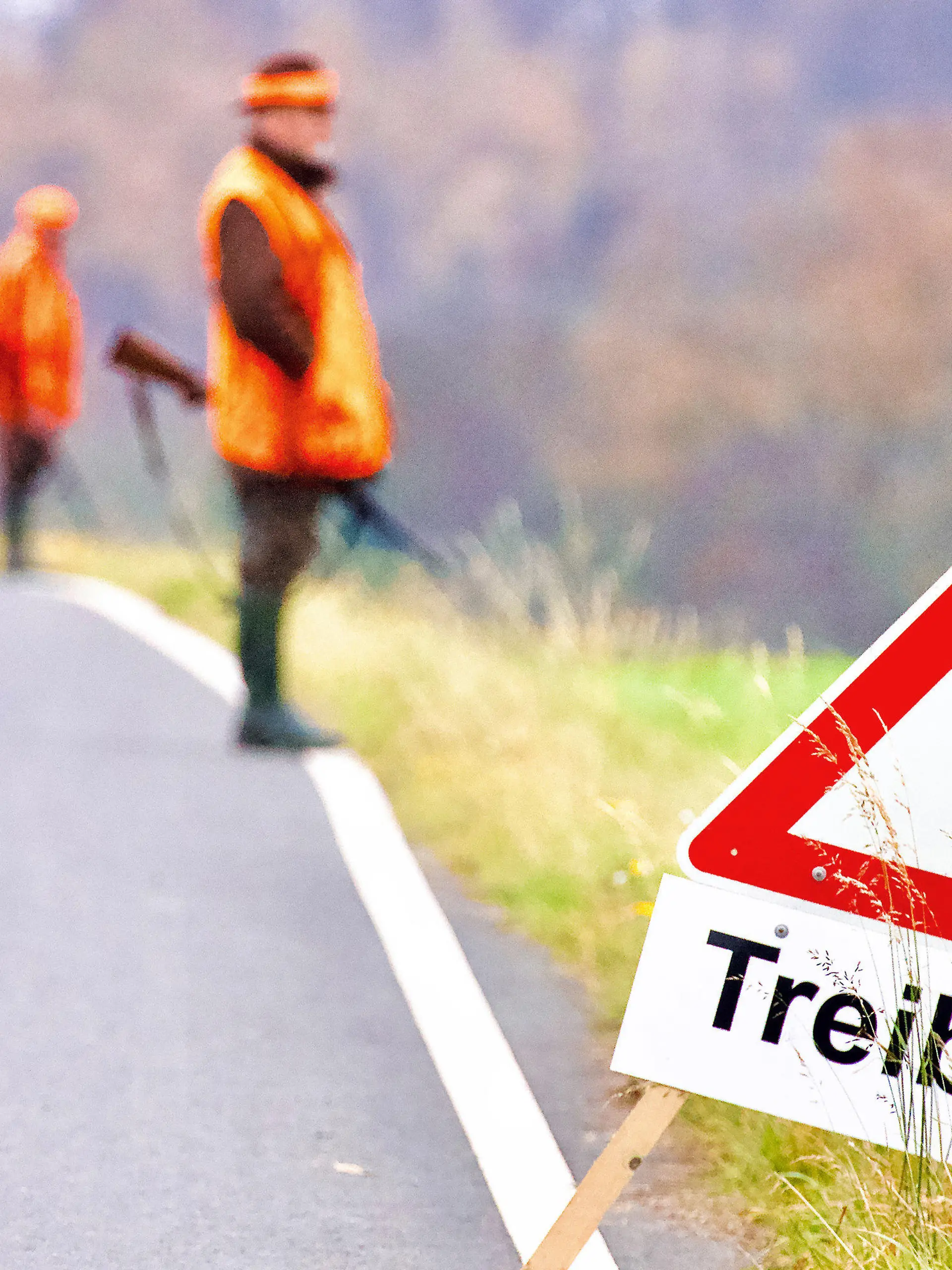 ARCHIV - 20.11.2021, Nordrhein-Westfalen, Wickede: Ein Warnhinweisschild steht während einer Treibjagd am Rande einer Straße. Im Hintergrund stehen Jäger mit Gewehren. (zu dpa: "Jäger erwarten wieder mehr Wildschwein-Abschüsse") Foto: Andreas Dunker/dpa +++ dpa-Bildfunk +++