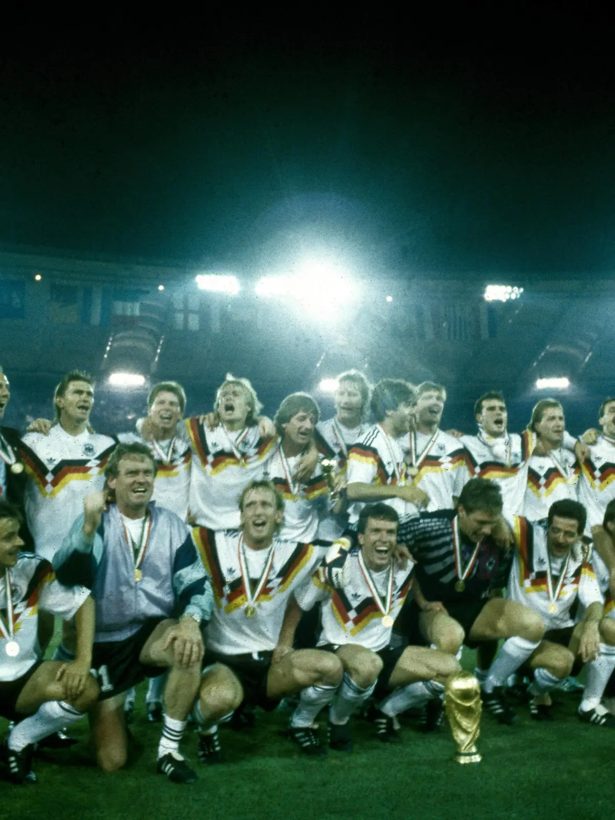 Weltmeisterschaft 1990. Die Deutsche Mannschaft mit WM Pokal nach dem Sieg im Finale am 8.7. in Rom, hi.v.li.: Holger Osieck, Franz Beckenbauer, Klaus Augenthaler, Stefan Reuter, Jürgen Klinsmann, Frank Mill, Guido Buchwald, Karl Heinz Riedle, Paul Steiner, Thomas Berthold, Andreas Köpke, Jürgen Kohler, Andreas Möller, Hansi Pflügler, Berti Vogts, vorn: Pierre Littbarski, Olaf Thon, Sepp Maier, Andreas Brehme, Lothar Matthäus, Bodo Illgner, Uwe Bein, Günter Hermann, Rudi Völler, Thomas Häßler, Raimond Aumann HM  