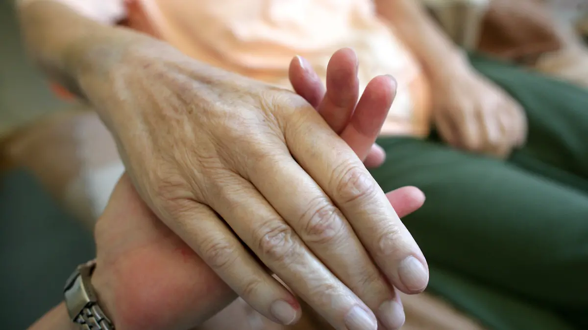 ARCHIV - Die Hand einer kranken Frau wird am 24.08.2009 in Magdeburg von einer Pflegerin gehalten. Bei der Vereinbarkeit von Familie und Beruf geht es in der alternden Gesellschaft längst nicht mehr nur um Kinderbetreuung. Immer mehr Menschen pflegen auch kranke Angehörige. In ihrem Leben ist häufig nichts mehr, wie es einmal war. Foto: Jens Wolf/lsw (zu dpa-KORR.: "Am Limit - Ein Leben zwischen Pflege und Job" vom 06.09.2010)  +++(c) dpa - Bildfunk+++