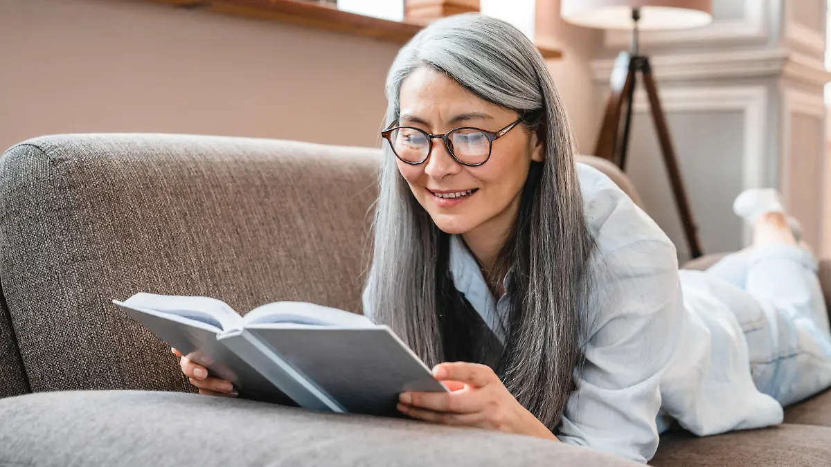 Frau liest einen Bestseller auf der Couch.