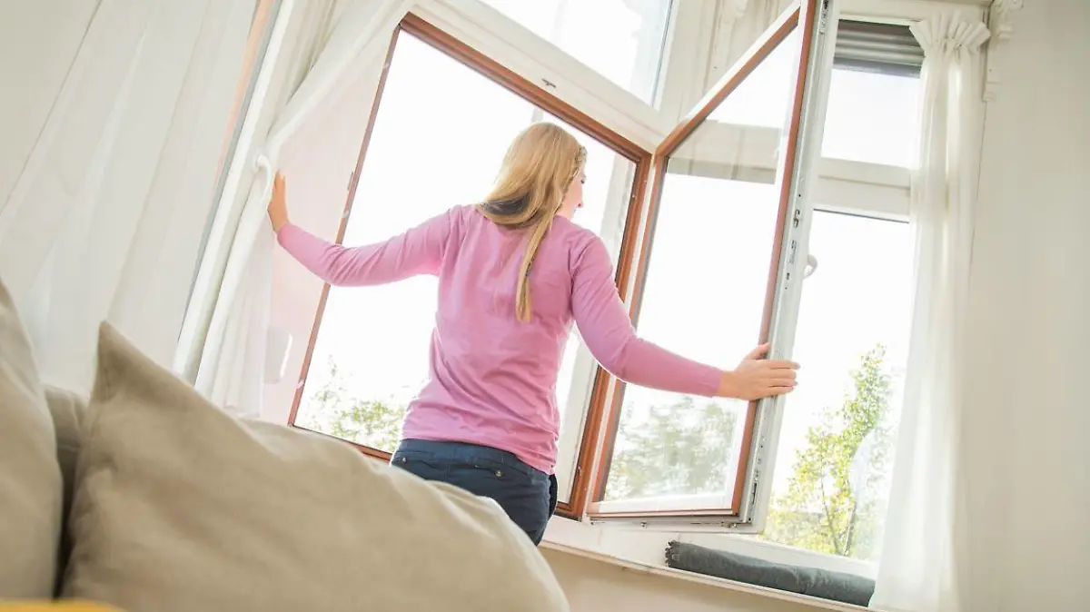 Frau lüftet im Wohnzimmer