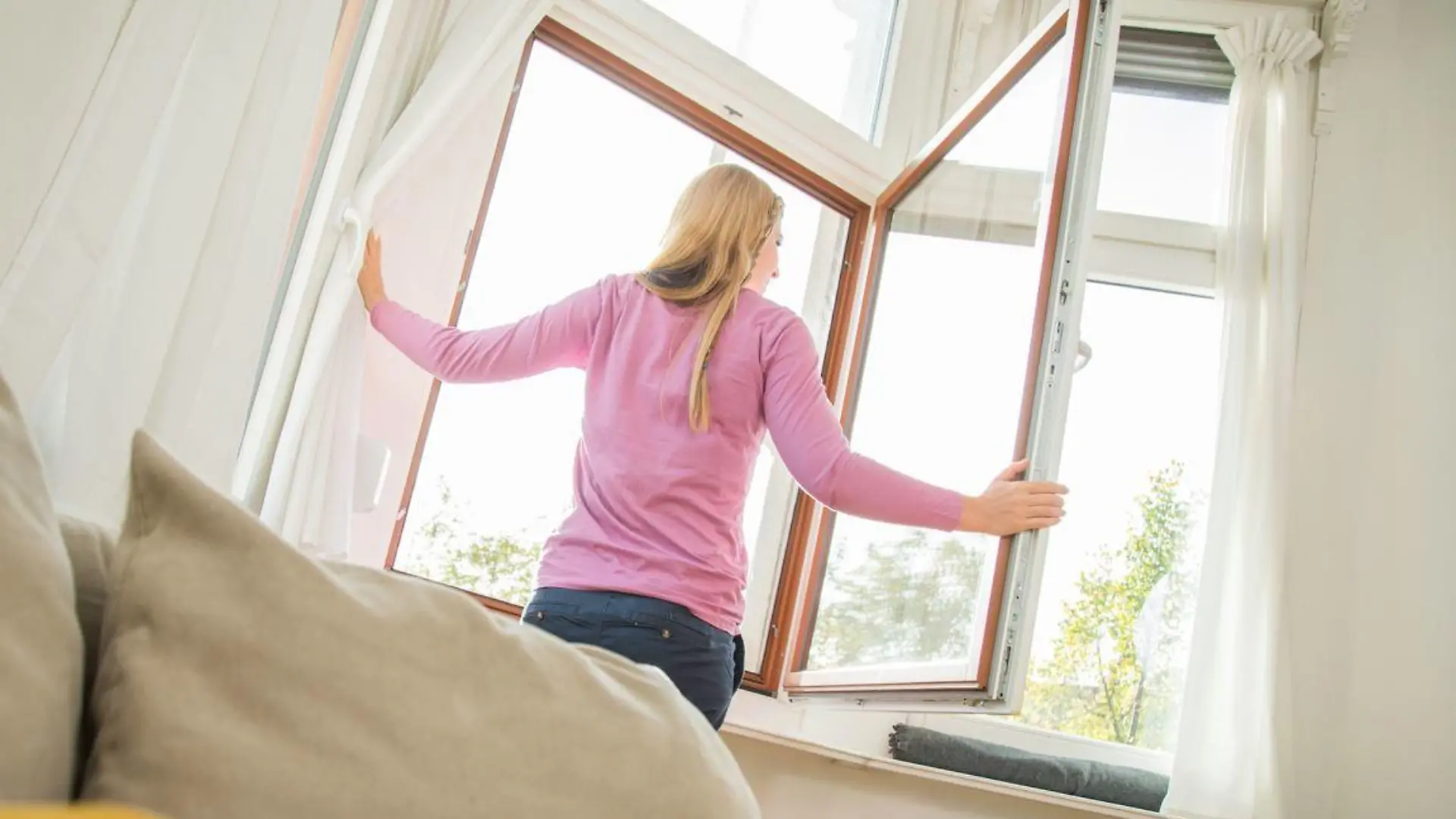 Frau lüftet im Wohnzimmer