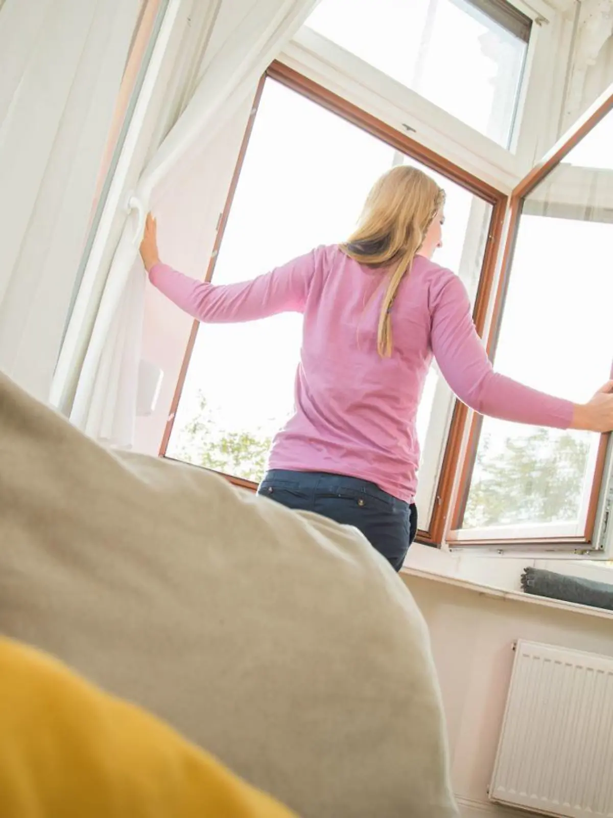 Frau lüftet im Wohnzimmer