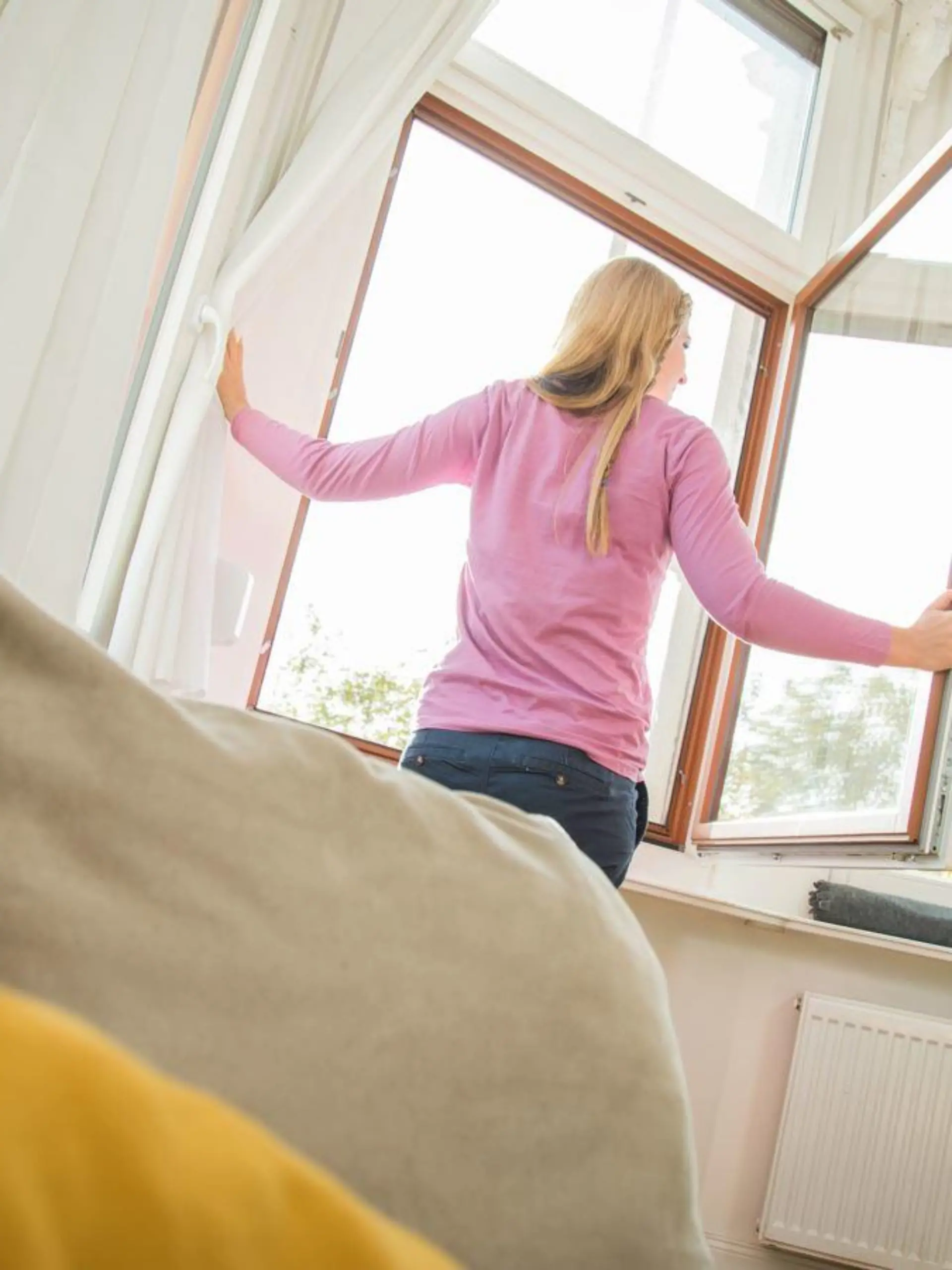 Frau lüftet im Wohnzimmer
