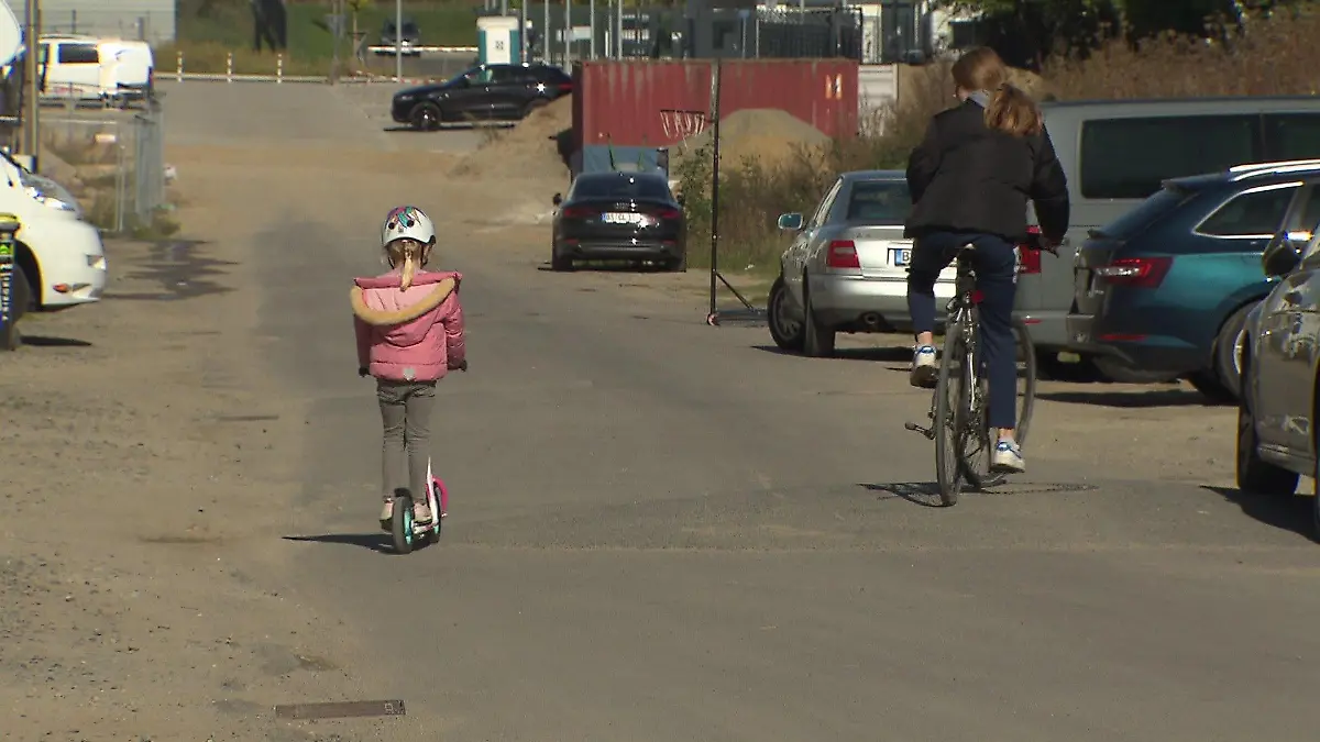 Zwei Mädchen auf Fahrrad und Roller fahren auf Baustellenstraße