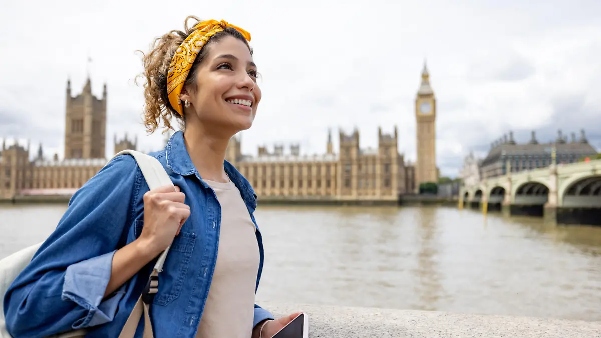Happy Latin American woman sightseeing in London around the Big Ben and smiling