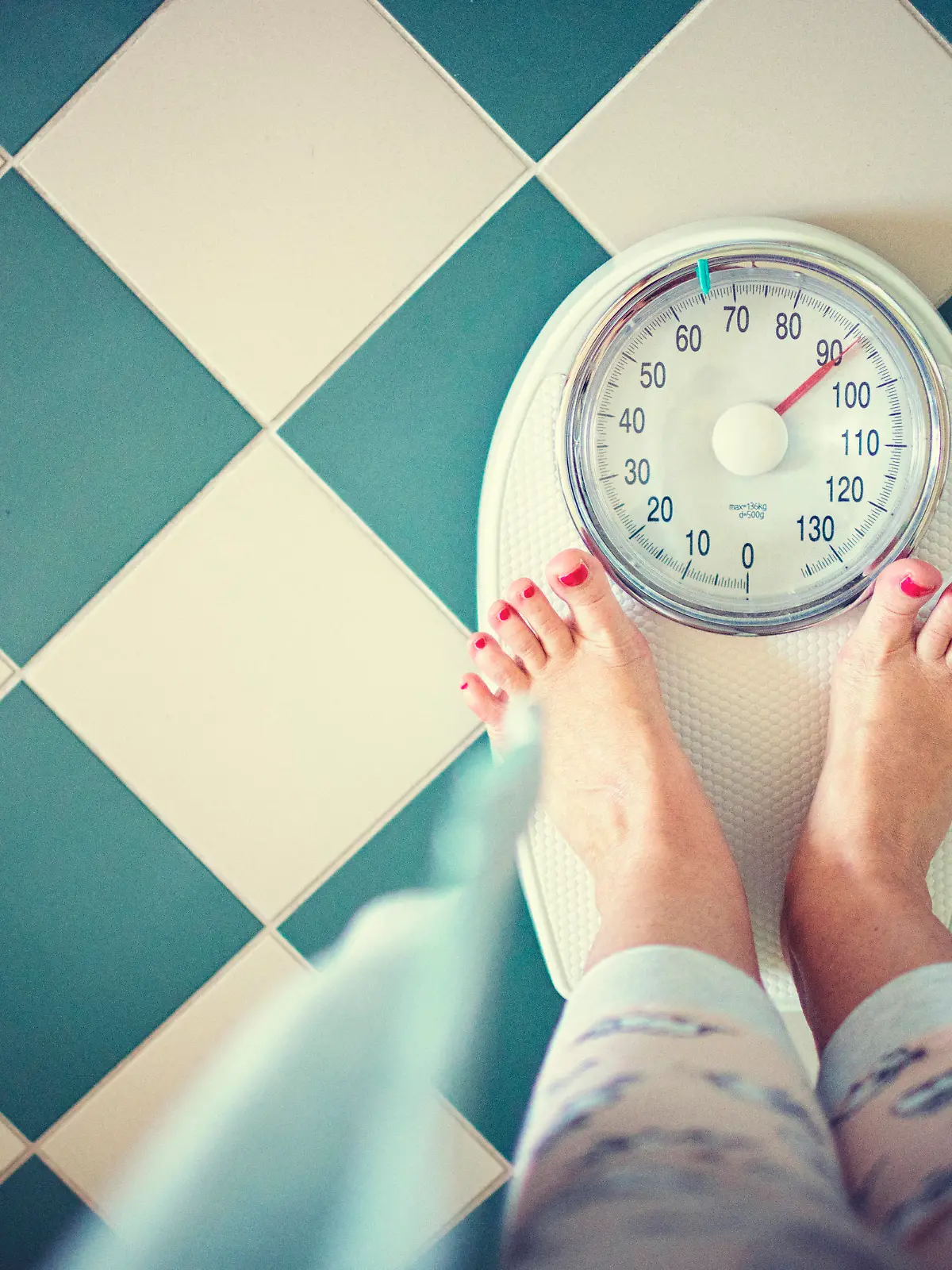 Woman stands in the bathroom on the scales in the morning