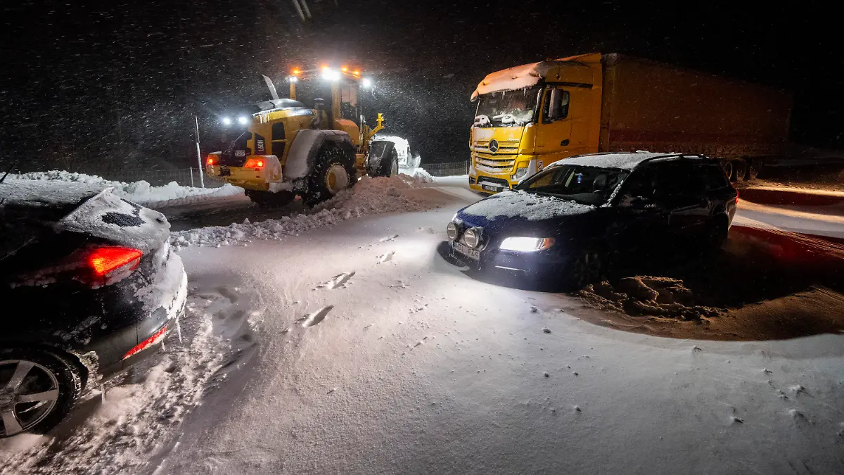 04.01.2024, Schweden, Horby: Mit Radladern wird der Schnee geräumt, während Autos und Lastwagen geborgen und Menschen mit dem Kettenfahrzeug der Home Guard (Teil der schwedischen Streitkräfte) in Ekerödsrasten auf der Europastraße 22 zwischen Hörby und Kristianstad in Südschweden in der Nacht zum Donnerstag, 4. Januar 2024, evakuiert werden. Europa erlebte am Mittwoch krasse Wetterkontraste: Extreme Kälte und Schneestürme führten zu Verkehrsbehinderungen und Schulschließungen in Skandinavien, während starke Winde und heftige Regenfälle in Westeuropa zu Überschwemmungen führten. Foto: Johan Nilsson/TT News Agency/AP/dpa +++ dpa-Bildfunk +++