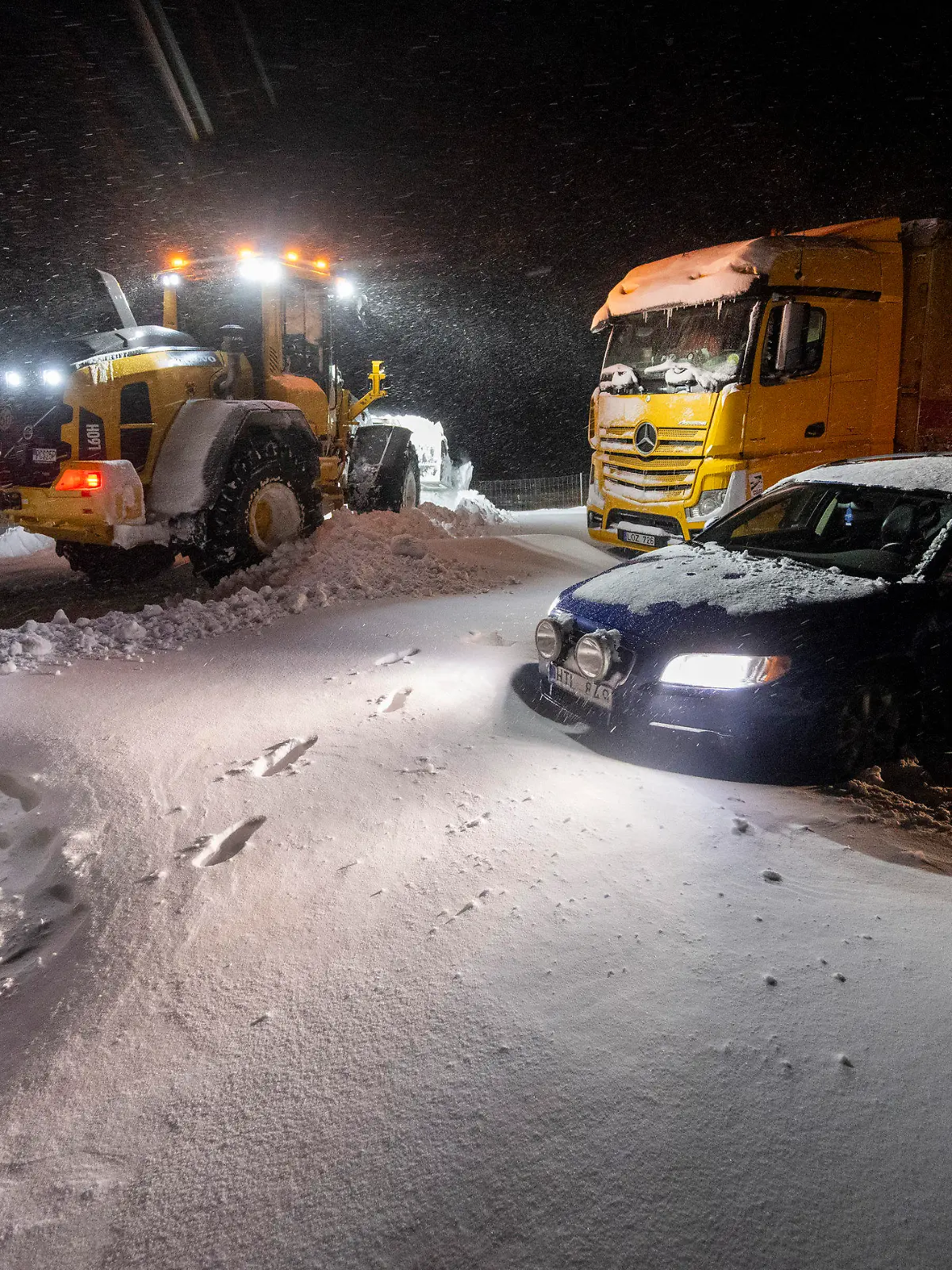 04.01.2024, Schweden, Horby: Mit Radladern wird der Schnee geräumt, während Autos und Lastwagen geborgen und Menschen mit dem Kettenfahrzeug der Home Guard (Teil der schwedischen Streitkräfte) in Ekerödsrasten auf der Europastraße 22 zwischen Hörby und Kristianstad in Südschweden in der Nacht zum Donnerstag, 4. Januar 2024, evakuiert werden. Europa erlebte am Mittwoch krasse Wetterkontraste: Extreme Kälte und Schneestürme führten zu Verkehrsbehinderungen und Schulschließungen in Skandinavien, während starke Winde und heftige Regenfälle in Westeuropa zu Überschwemmungen führten. Foto: Johan Nilsson/TT News Agency/AP/dpa +++ dpa-Bildfunk +++
