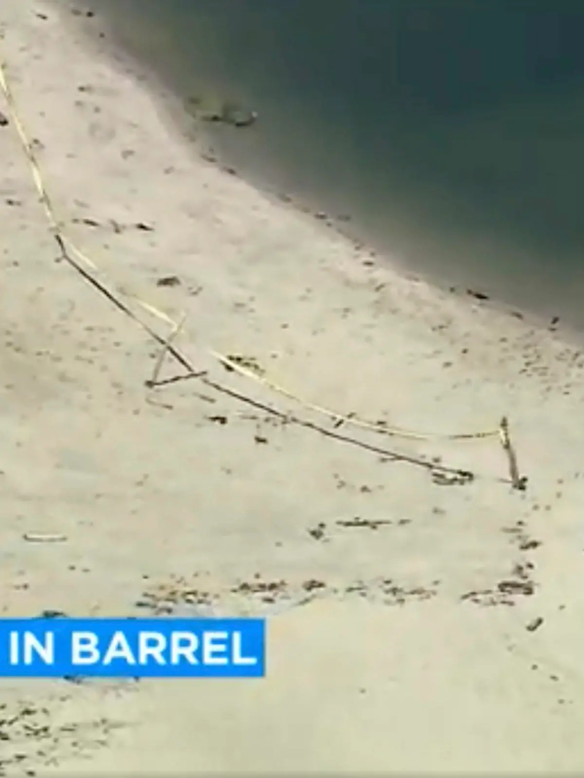 This image taken from video and provided by KABC-7 TV shows law enforcement officers stand by a barrel at Malibu Lagoon on Monday, July 31, 2023. A body was discovered inside a barrel, on Monday and detectives are investigating the circumstances around the death. (KABC-7 via AP)