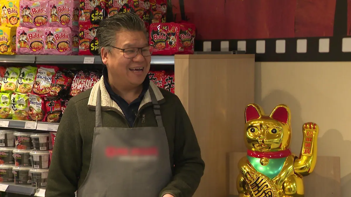 Ly Phung steht neben einer Winkekatze