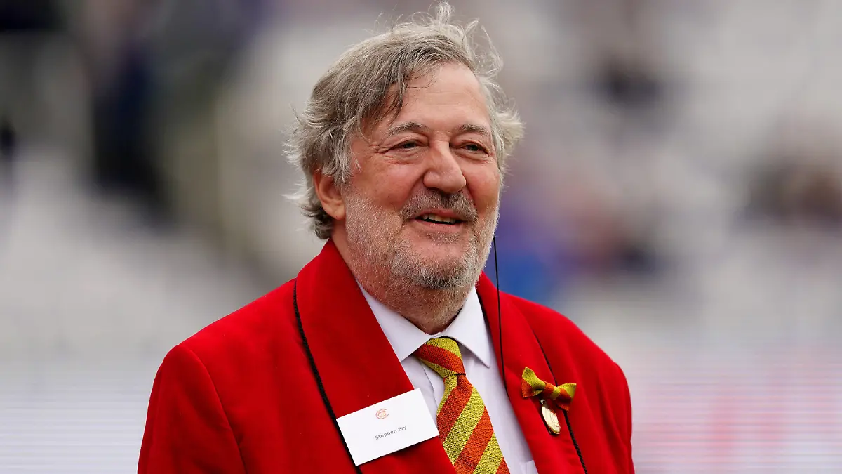 ARCHIV - 29.06.2023, Großbritannien, London: Stephen Fry, Präsident des Marylebone Cricket Club (MCC) und Schauspieler aus Großbritannien, trägt am zweiten Tag des zweiten Ashes-Testspiels im Lord's zu Ehren der Ruth Strauss Stiftung einen roten Anzug. (zu dpa: «Britischer Schauspieler Stephen Fry fordert Aus für Bärenfellmützen») Foto: Mike Egerton/PA Wire/dpa +++ dpa-Bildfunk +++