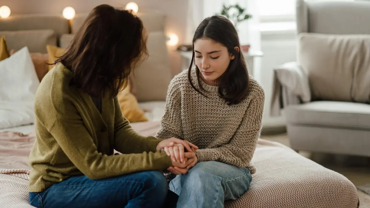 Teenage girl sharing problems with her mother in the room.