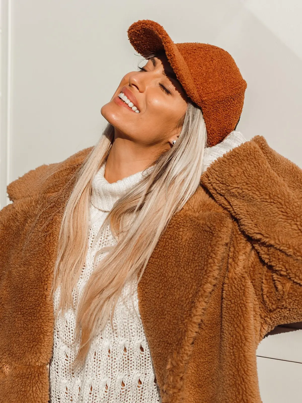 Frau trägt den Mantel-Trend Teddymantel und lacht.