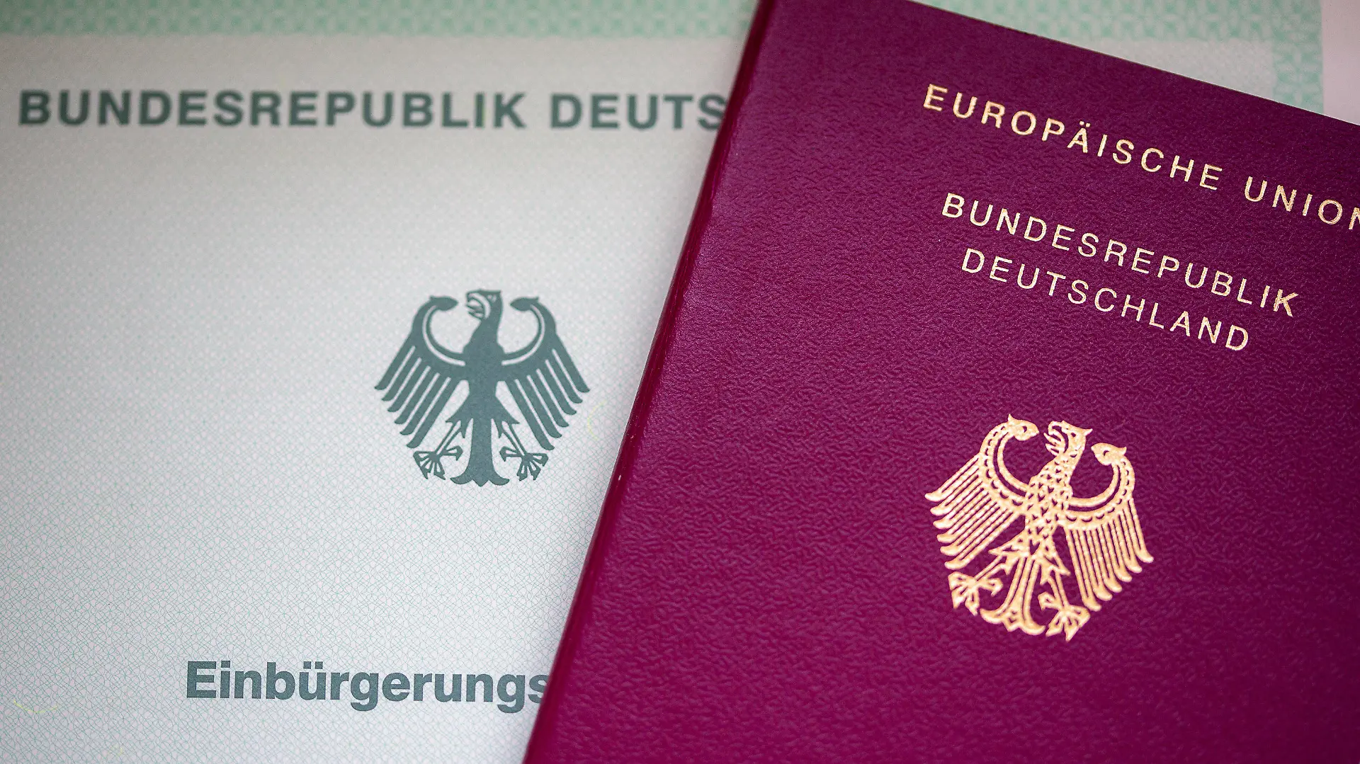 ARCHIV - 22.05.2023, Berlin: Eine Einbürgerungsurkunde der Bundesrepublik Deutschland (l) und ein deutscher Reisepass liegen auf einem Tisch. Weil sie Gebühren für die Einbürgerung von Ausländern für sich persönlich behalten haben soll, ermittelt die Staatsanwaltschaft gegen eine frühere Mitarbeiterin des Landkreises Osnabrück. (zu dpa «Mitarbeiterin der Ausländerbehörde soll Gebühren veruntreut haben») Foto: Fernando Gutierrez-Juarez/dpa +++ dpa-Bildfunk +++