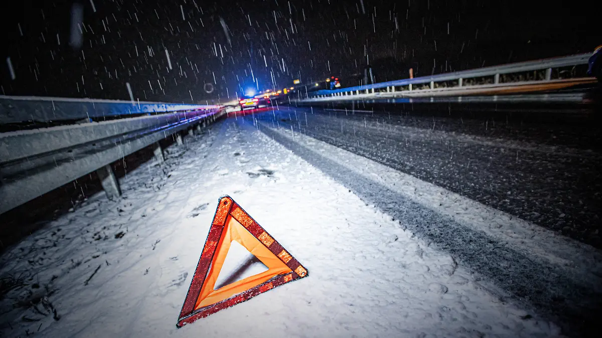 Schneechaos im Ostalbkreis, Symbolbild von einem Warndreieck im Schnee, im Hintergrund sichert die Polizei einen Glätteunfall ab. Essingen *** Snow chaos in the Ostalbkreis, symbolic picture of a warning triangle in the snow, in the background the police secures a slippery road accident from Essingen Copyright: xSimonxAdomatx 