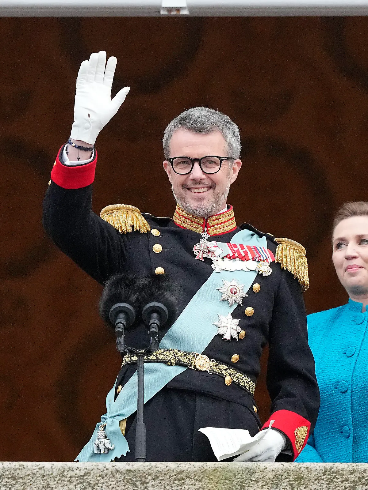 14.01.2024, Dänemark, Kopenhagen: König Frederik X. von Dänemark winkt vom Balkon des Schlosses Christiansborg, während die dänische Ministerpräsidentin Mette Frederiksen zusieht. Frederik X. ist zum neuen König von Dänemark ausgerufen worden. Ministerpräsidentin Mette Frederiksen proklamierte den Thronwechsel am Sonntag auf dem Balkon von Schloss Christiansborg in Kopenhagen. Foto: Martin Meissner/AP +++ dpa-Bildfunk +++