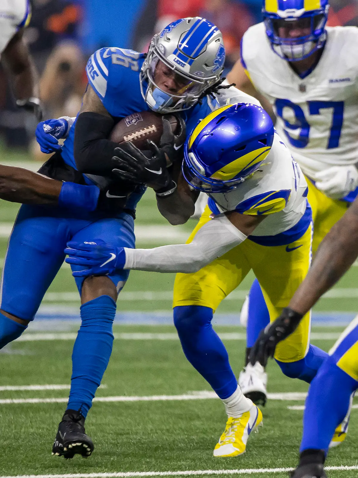 Jan 14, 2024; Detroit, Michigan, USA; Detroit Lions running back Jahmyr Gibbs (26) is tackled by Los Angeles Rams linebacker Ernest Jones (53) and linebacker Michael Hoecht (97) during the first half of a 2024 NFC wild card game at Ford Field. Mandatory Credit: David Reginek-USA TODAY Sports