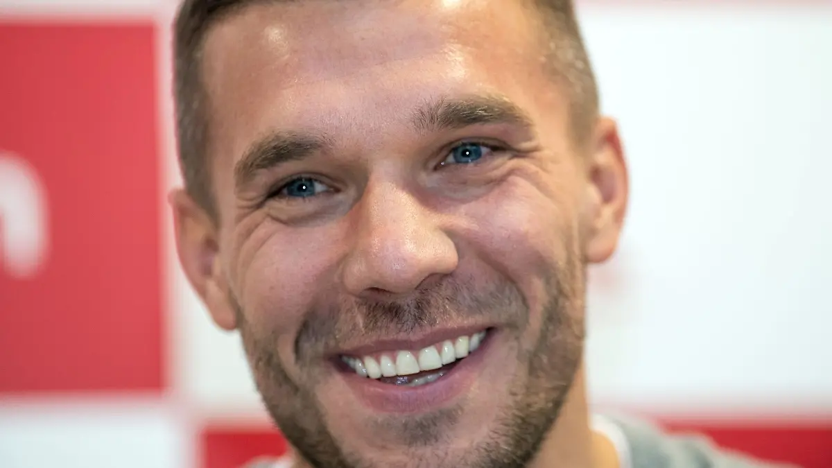 Der frühere Fußall-Nationalspieler Lukas Podolski lächelt bei einer Pressekonferenz.
