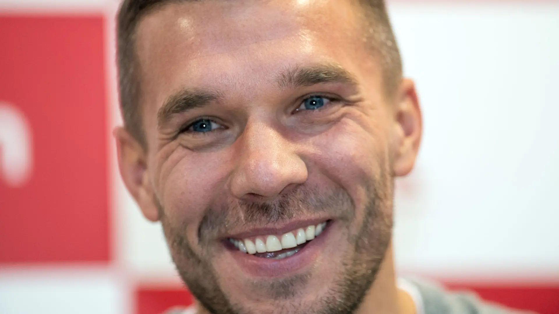 Der frühere Fußall-Nationalspieler Lukas Podolski lächelt bei einer Pressekonferenz.