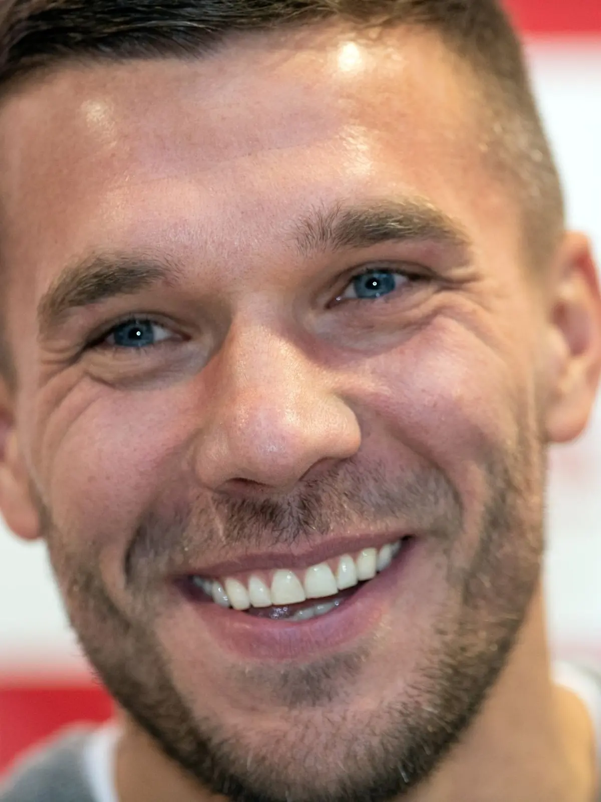Der frühere Fußall-Nationalspieler Lukas Podolski lächelt bei einer Pressekonferenz.