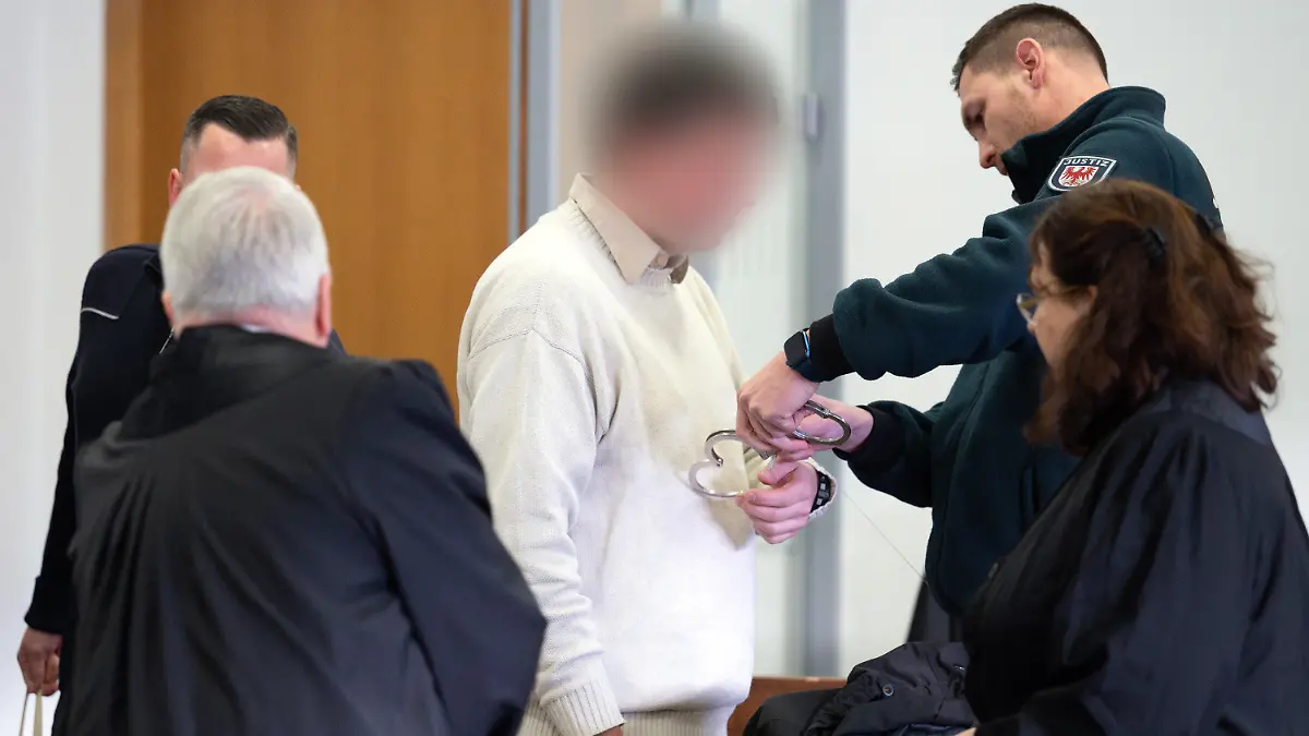 15.01.2024, Brandenburg, Potsdam: Einer der beiden Angeklagten (M) kommt vor Beginn der Hauptverhandlung wegen gemeinschaftlichen Mordes in den Gerichtssaal 8 des Potsdamer Landgerichts. Die beiden Angeklagten sollen im Mai 2023 auf der Autobahn A9 zwischen Brück und Beelitz die 40 Jahre alte ehemalige Lebensgefährtin eines Angeklagten mit einer Schusswaffe ermordet haben. Foto: Soeren Stache/dpa - ACHTUNG: Person(en) wurde(n) aus rechtlichen Gründen gepixelt +++ dpa-Bildfunk +++