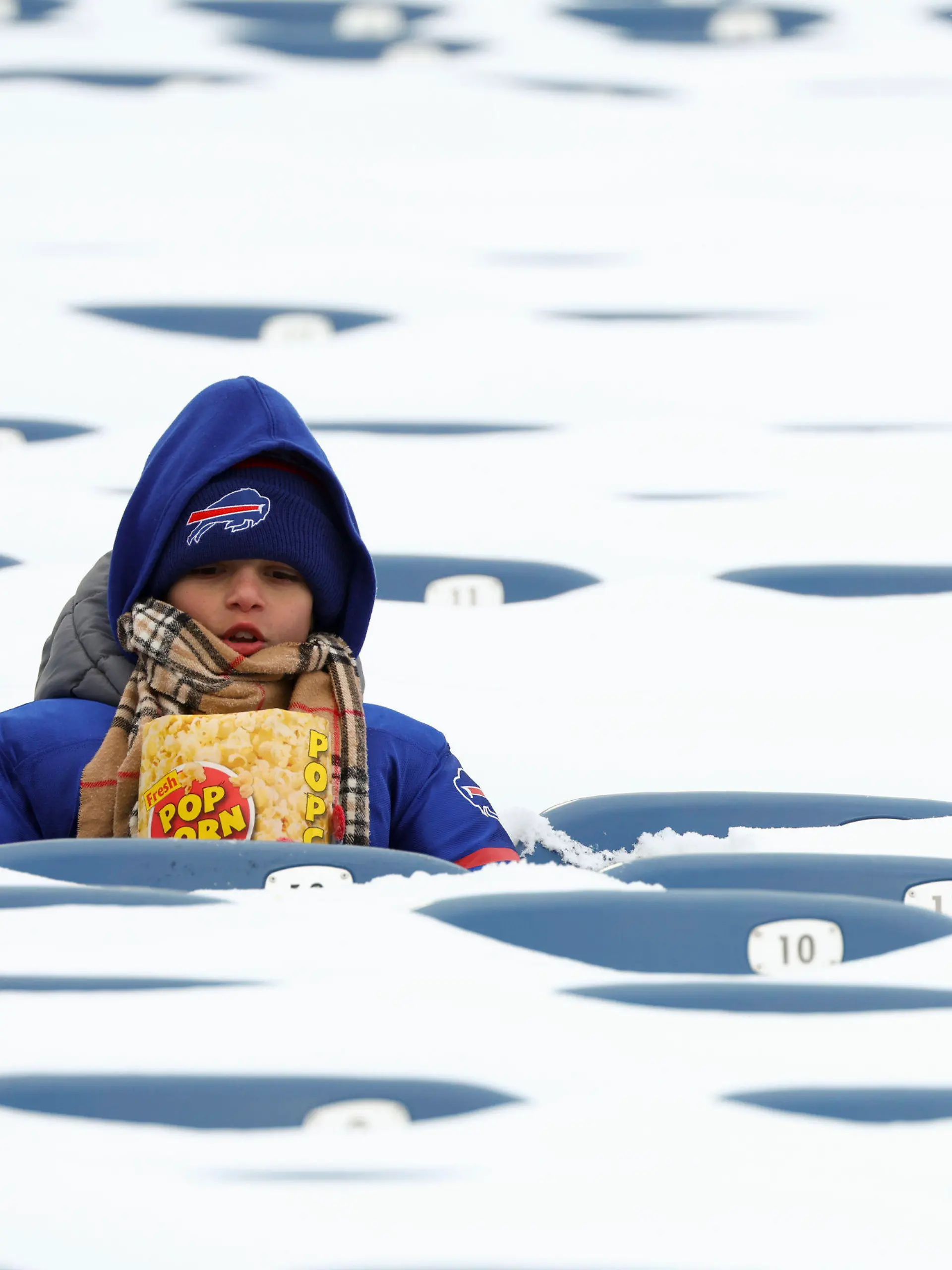 A Buffalo Bills fan sits amongst snow covered seats while waiting for the start an NFL wild-card playoff football game between the Buffalo Bills and the Pittsburgh Steelers, Monday, Jan. 15, 2024, in Buffalo, N.Y. (AP Photo/Jeffrey T. Barnes)