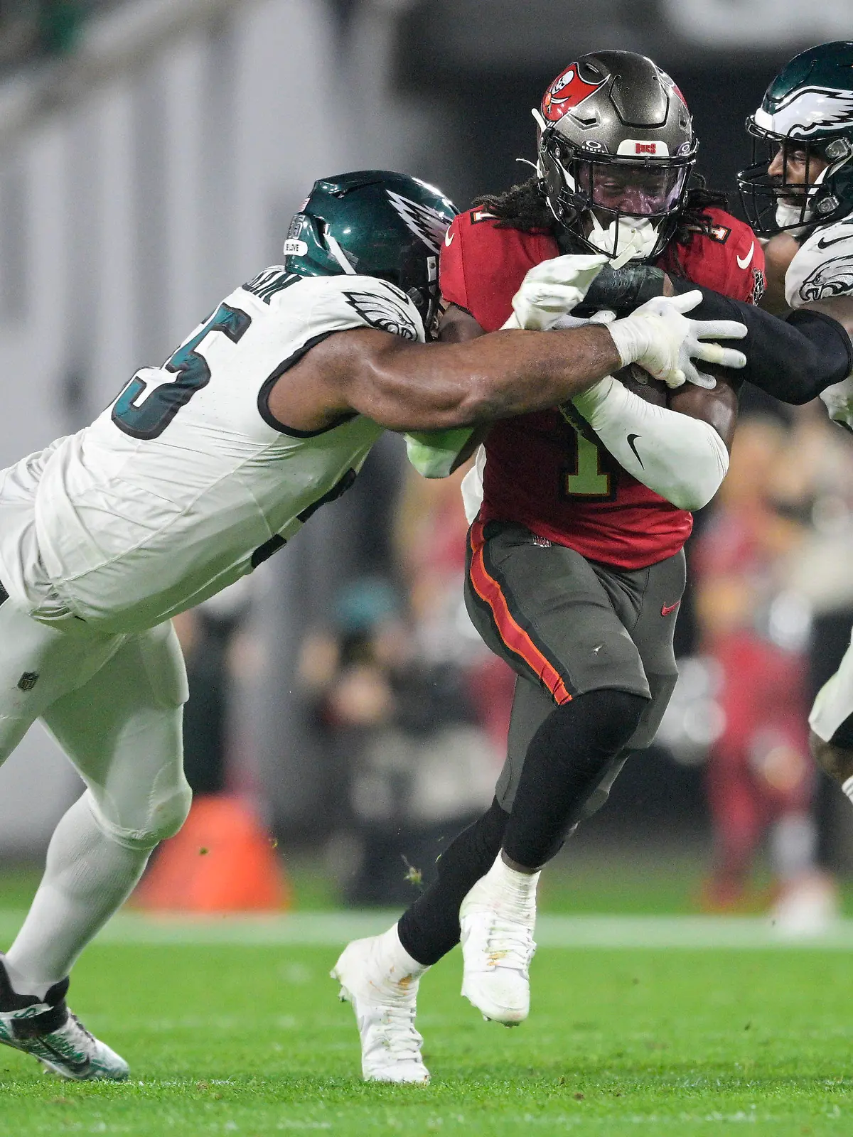 15.01.2024, USA, Tampa: American Football: Profiliga NFL, Play-off-Runde, Viertelfinal-Qualifikation, Tampa Bay Buccaneers - Philadelphia Eagles. Rachaad White (1), Running Back der Tampa Bay Buccaneers, in Aktion gegen Philadelphia Eagles Defensive End Brandon Graham (55) und Linebacker Zach Cunningham (52). Foto: Phelan M. Ebenhack/AP/dpa +++ dpa-Bildfunk +++