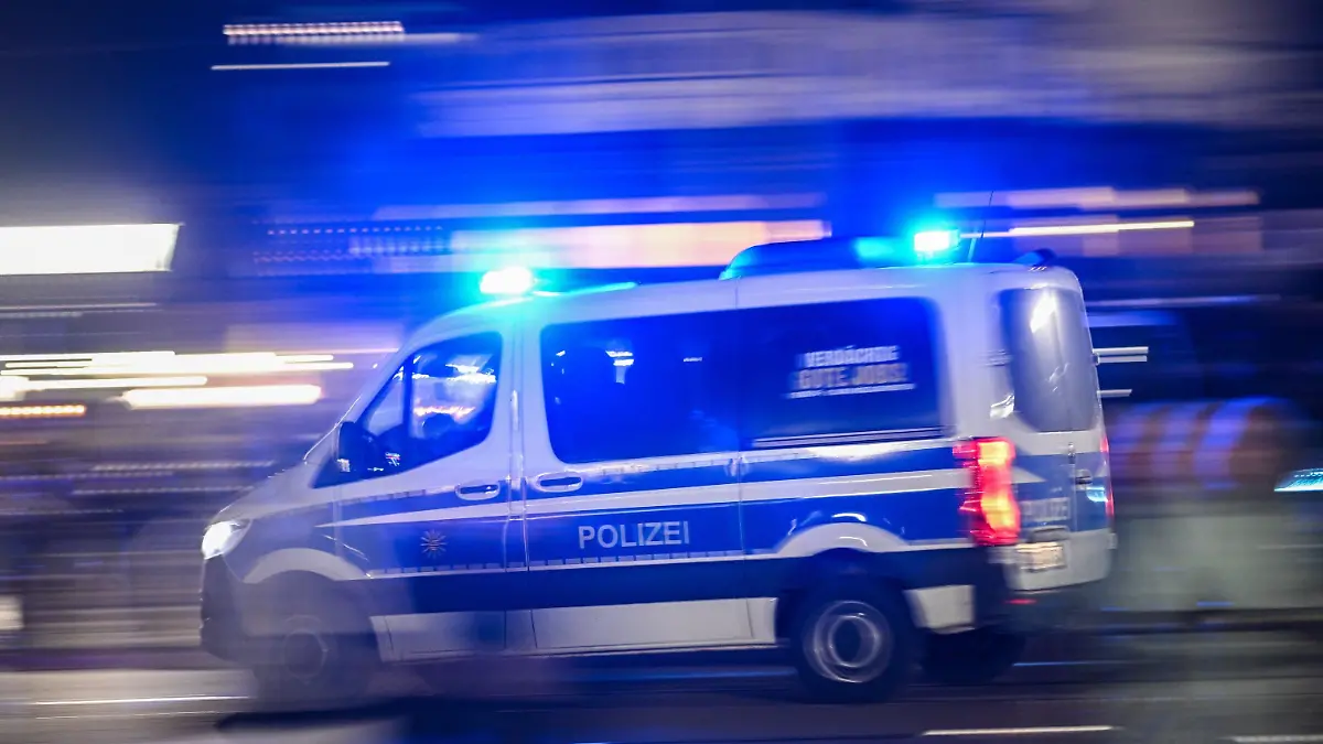 18.12.2023, Sachsen, Dresden: Ein Polizeiauto fährt mit Blaulicht am Rande einer Demonstration der rechtsextremistischen Bewegung Pegida über die Augustusbrücke. Foto: Robert Michael/dpa +++ dpa-Bildfunk +++