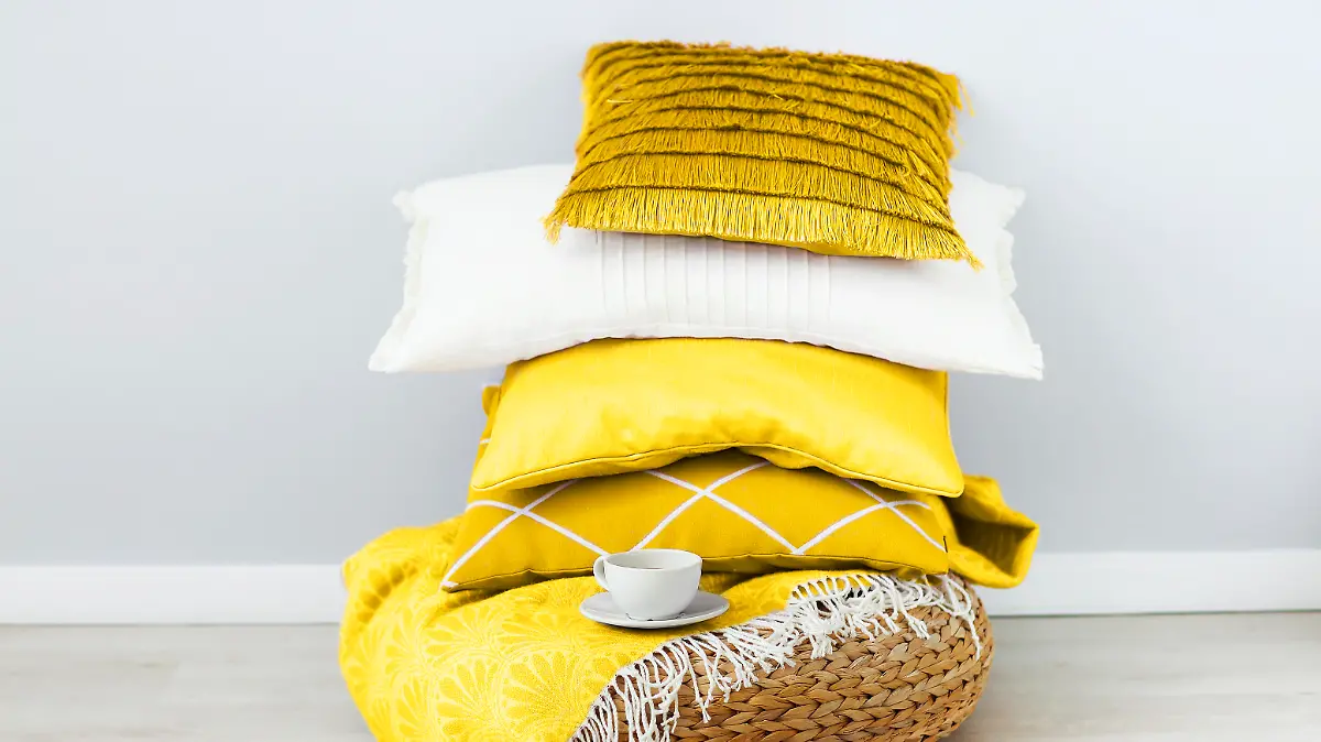 Pink and white pillows and cup of coffee on the wall background. Close up