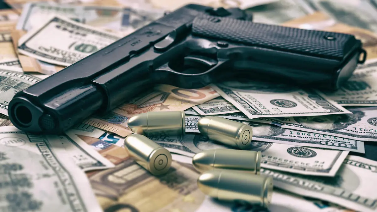 Pistol and bullets on dollar and euro banknotes background, closeup view. Criminal money. Black money and protection, mafia and corruption concept,