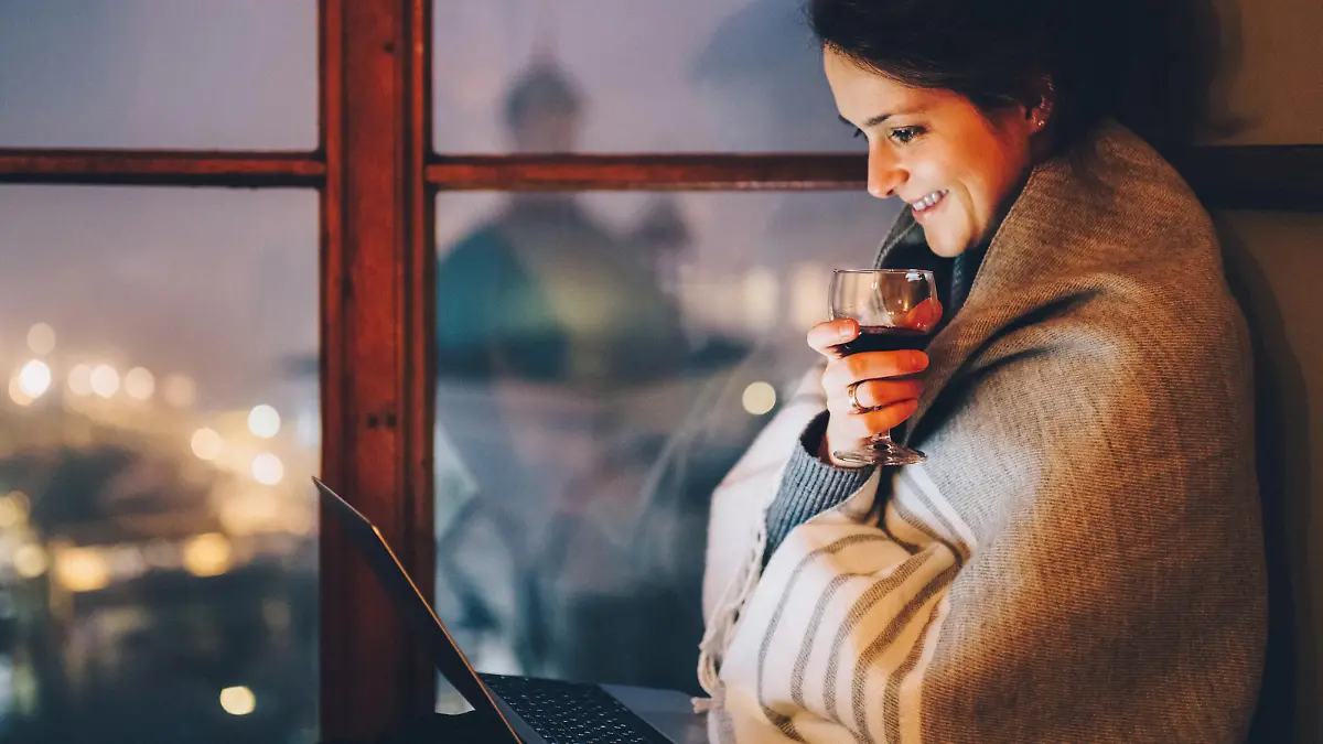 Relaxed woman at the window sill enjoying a movie on the lap top