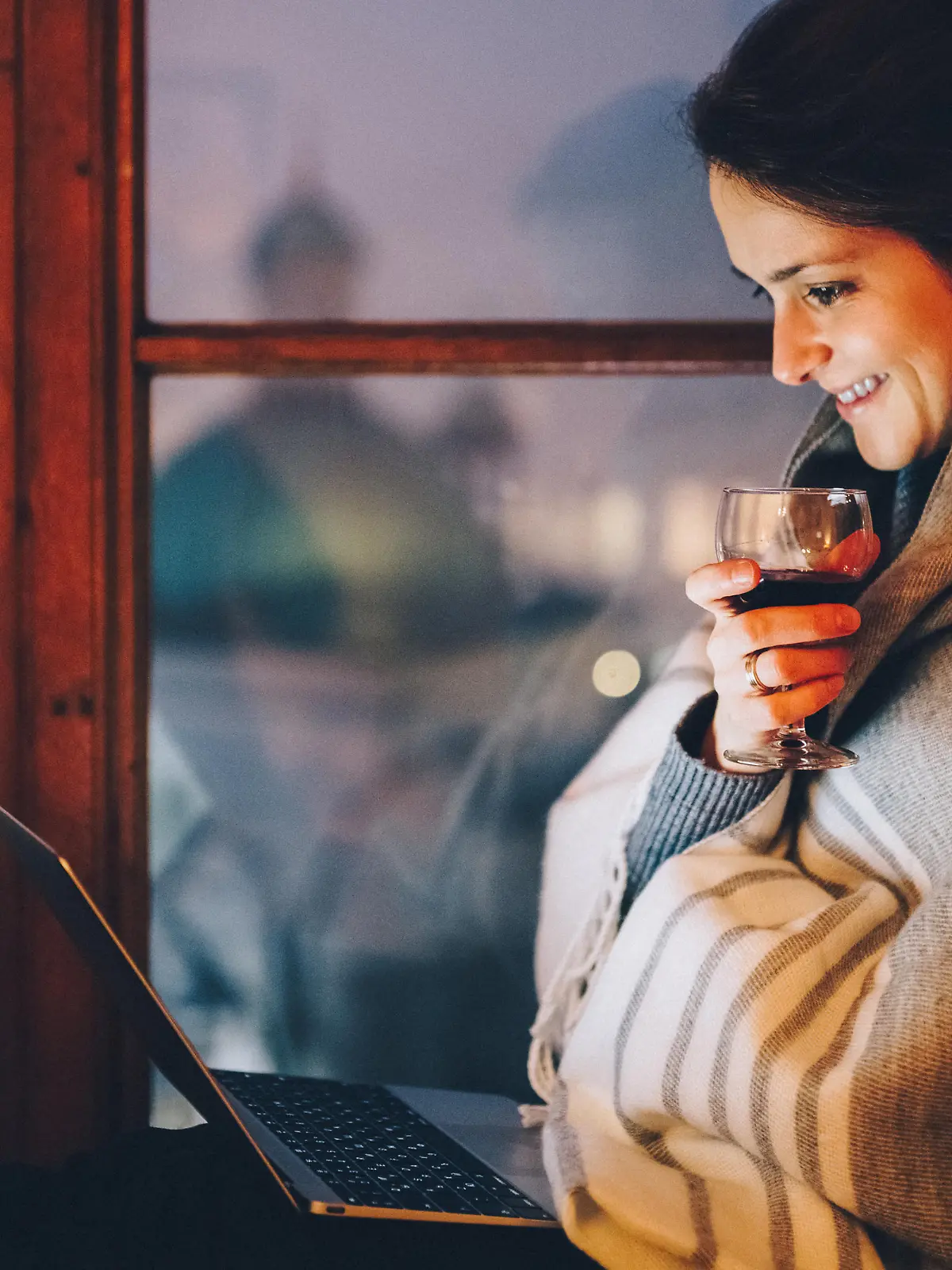 Relaxed woman at the window sill enjoying a movie on the lap top